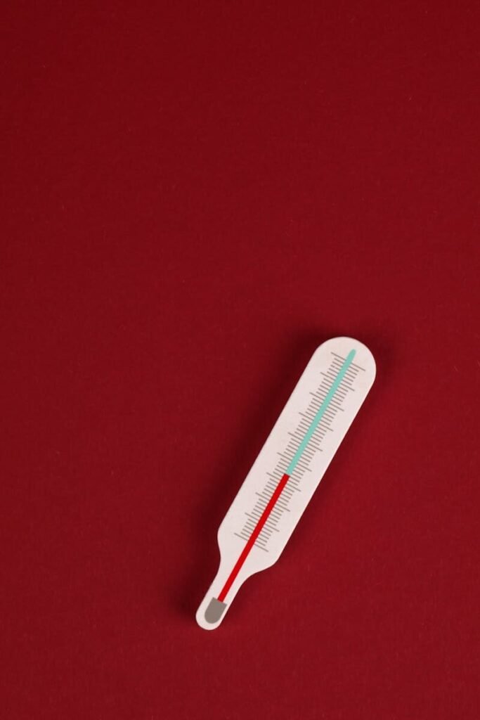Vertical shot of a thermometer on a bright red background, ideal for healthcare themes.