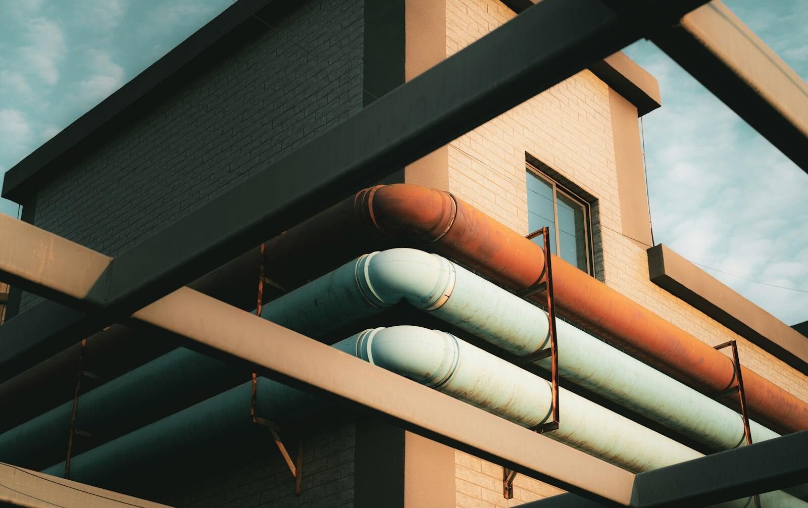 Contemporary architecture featuring exposed colorful pipes against a tiled building exterior.